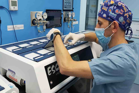 Picture of the interior of a fertility laboratory, representing the capabilities of an IVF fertility center.  The person is wearing gloves, a head covering and a blue smock.