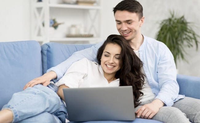 Picture of a happy couple having a video conference with their fertility doctor in Costa Rica.  The couple is smiling and looking into a laptop computer.